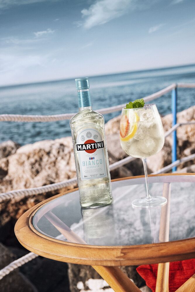 A bartender pouring tonic into a glass of MARTINI Bianco with ice.